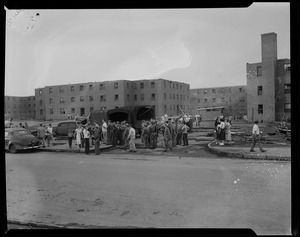 Military men talking with people in front of housing developments