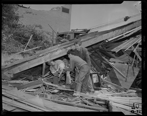 Three men rescuing a cat from wreckage