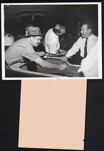 Cool Gambler. In an air conditioned casino in sizzling Las Vegas, Nev., a visitor takes his Sunday afternoon exercise at the craps table. He keeps an unlit cigar clenched in his mouth and his hat on -- whatever happens to his shirt.