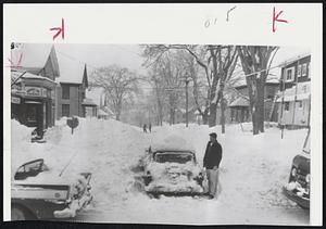This is a very familiar scene in the Bangor, Maine, area. A motorist is standing by his mired auto waiting for a wrecker to come pull him out. The street in the background hasn't been plowed since early.