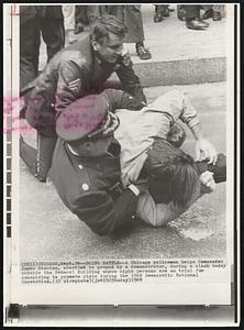 Doing Battle--A Chicago policeman helps Commander James Riordan, wrestled to ground by a demonstrator, during a clash today outside the Federal Building where eight persons are on trial for conspiring to promote riots during the 1968 Democratic National Convention.