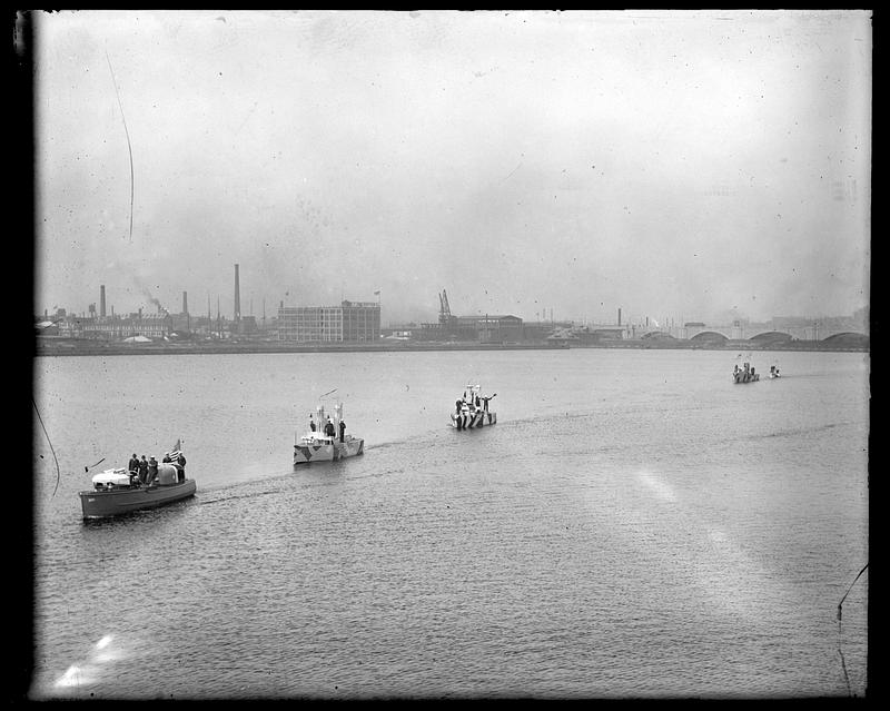 Boats in a line going up the Charles River, some painted with dazzle camouflage