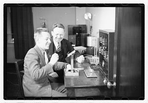 A boy sitting next to a man using an unidentified device