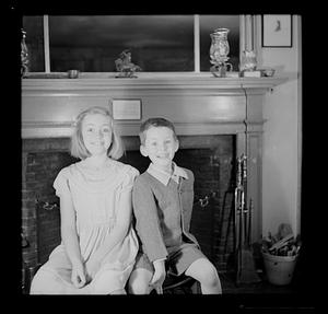 Two young children by fireplace