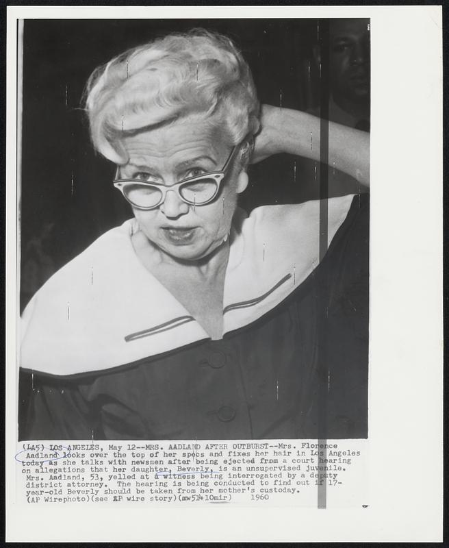 Mrs. Aadland After Outburst--Mrs. Florence Aadland looks over the top her specs and fixes her hair in Los Angeles today as she talks with newsmen after being ejected from a court hearing on allegations that her daughter, Beverly, is an unsupervised juvenile. Mrs. Aadland, 53, yelled at a witness being interrogated by a deputy district attorney. The hearing is being conducted to find out if 17-year-old Beverly should be taken from her mother's custody.