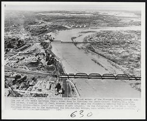 Threatened Area -- The flood waters of the Missouri River, already coming out of its banks upstream (top), moves down to threaten the Omaha-Council Bluffs, Ia., area. The stream, standing over 28 feet, courses south with only the floodwalls keeping the water from the twin cities--Omaha (left) and Council Bluffs (right). In the foreground is the Union Pacific railroad bridge and in the background the Ark-Sar-Ben bridge, main artery from vehicular traffic.
