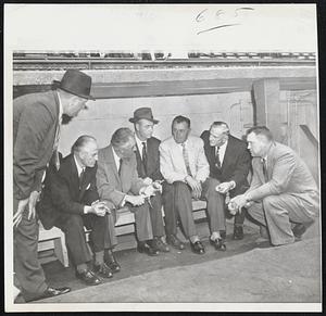 Baseball Commissioner Ford Frick confers with umpires and the managers of the Dodgers and Yankees in the Dodger dugout at Ebbets Field just before the second game of the World Series was postponed today because of rain. Left to right, Umpires Tom Gorman and Babe Pinelli, Frick, Manager Walter Alston of the Dodgers, Umpire Ed Runge, Manager Casey Stengel of the Yanks, and Umpire Hank Soar.