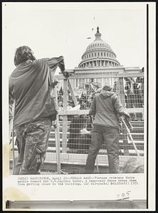 Medals Away--Vietnam veterans throw medals toward the U.S. Capitol today. A temporary fence keeps them from getting close to the building.