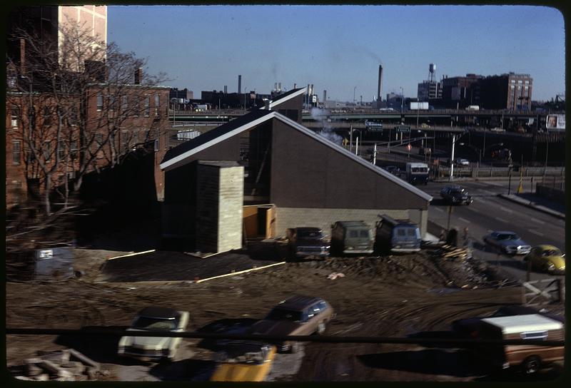 A building with cars parked in a dirt lot adjacent to it