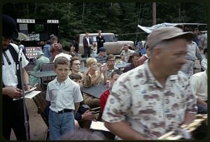 Spectators seated and clapping at tables during the antique car rally BBQ