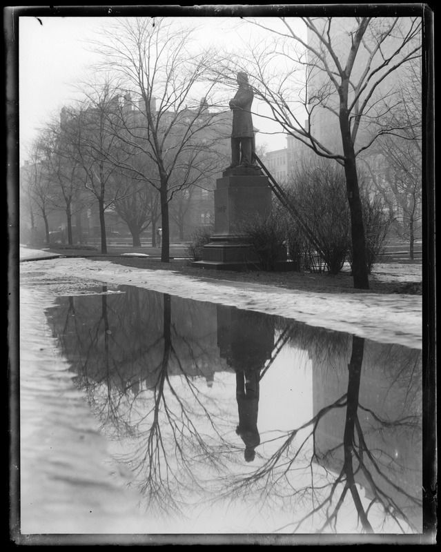 Thawing in the Public Garden showing Summers' statue reflecting in puddle of water on Boylston St. side of the Garden