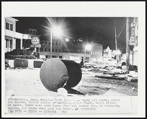 Flood Damage -- Empty oil tanks, thick ice blocks, litter center of Norwich, after flood, which killed at least. Tanks were torn loose from oil dealer lot, by rampaging waters, let loose when park dam broke.