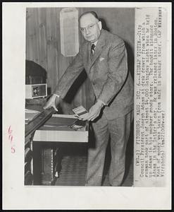 Kidnap Victim - City Council President Joseph Adams at desk drawer from which a gunman took part of almost $4,000 Saturday night when he held up Adams in his package goods store. The bandit kidnapped Adams in the latter's car. He was released later in Boston. Most of money was taken from safe in package store.