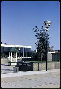 A mustached face wearing a hat and bowtie on a pole, gazebo in background