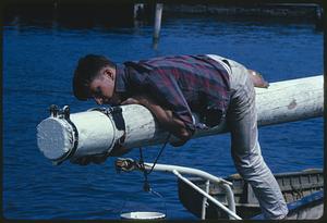 Boy climbing pole on ship