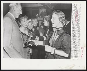 Divided Attention-- Dorothy Warren, daughter of Chief Justice and Mrs. Earl Warren, is seemingly unaware of the big smile and handshake she is getting from Margaret Truman. Her attention at the moment is directed to former Secretary of State Dean Acheson, standing in last night's receiving line at a benefit birthday party for former President Harry Truman. Margaret's parents stand next to her and the woman talking to Mrs. Truman is unidentified.