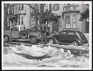 Garage Men prepare parked auto for towing from Thomas Park in Dorchester Heights area, South Boston. Autos were towed away when they impeded snow removal work in preparation for tomorrow's parade in South Boston.