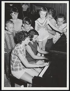 Plum Island Infantile Paralysis Carole Harrison 13 Beverly Carolyn Cody 13 Woburn (seated) play piano as other campers gather round to sing