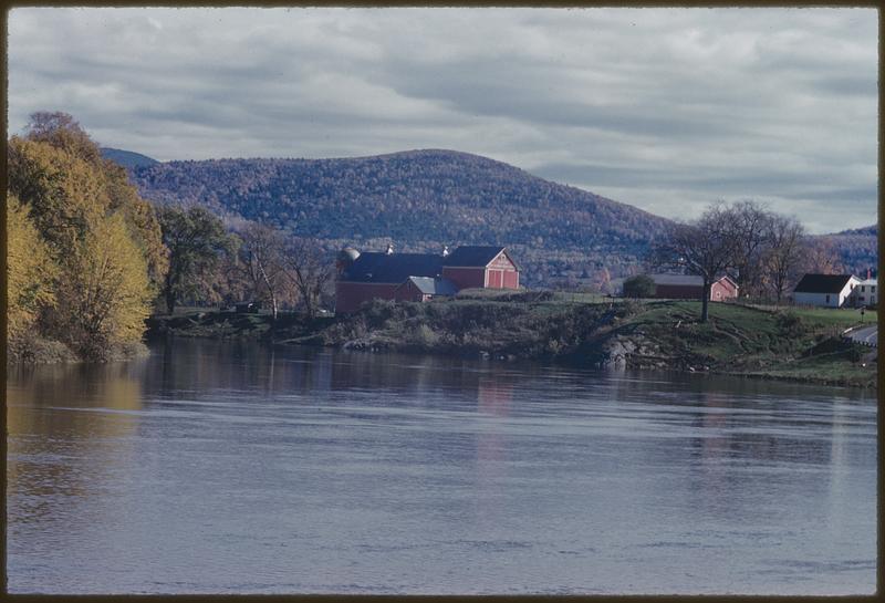 View across lake of farm and hills