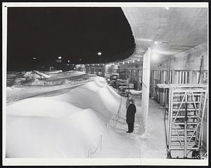 Drifts Piled Up from three storms at the international arrival and departure section of Logan Airport yesterday. The actual size of the drifts can be judged from the two men standing in the foreground.