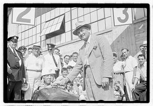 A man shaking hands with a boy in a soap box car
