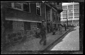 Man with hat walks up the sidewalk, looking back