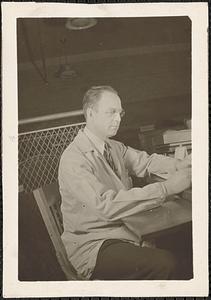 A man with glasses on sits at a desk