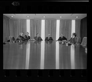 Boston Company executives meet around shiny conference table, downtown Boston
