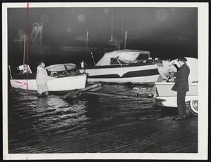 Boston Marina Prepares for Hurricane Donna's possible fury by beaching pleasure craft. Here, Frank Umano of Braintree, left, helps Robert Tabor of Squantum, right, pull a boat ashore while an unidentified guard holds a flashlight. Hundreds of craft were docked during the early morning hours.