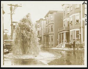It was about 6:30 this morning when George Dixon, Traveler cameraman, found this geyser spouting from a broken hydrant, almost as high as the houses at the corner of Raven street and Crescent avenue, Dorchester. Cellars were flooded on Crescent avenue and the lower photo recalled New England flood scenes as a horse plodded through the rushing water. Police said hydrant was a victim of a hit-and-run driver.