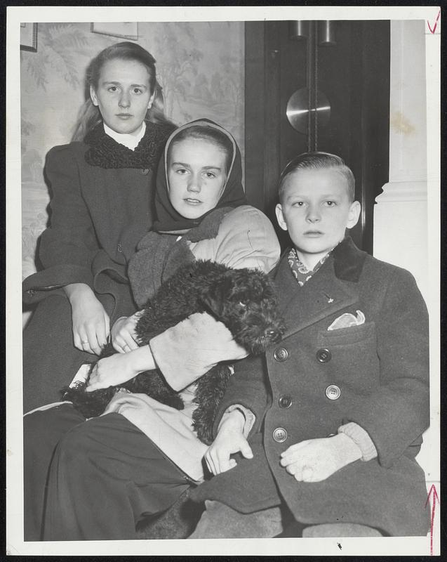 Fire Drives Out Ex-Governor and Family-An early morning fire which did $3500 in damage to the home of former Gov. and Mrs. Maurice J. Tobin in Jamaica Plain was discovered by their eldest daughter, Helen Louise, 14, shown (left) with her sister, Carol Ann, 13, and her brother Maurice, Jr., 10. Carol Ann holds their new Kerry Blue terrier, Galty, who was found unhurt in the house after the fire. At right, Tobin inspects charred studding revealed by torn-out living room wal, indicating how far fire starting in cellar had spread up through walls.