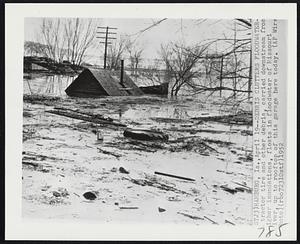 Debris Clutters Floodwater-A tractor tire and other debris, carried downstream from higher inundations, floats in floodwater of Missouri River, up to rooftop of this garage here today.