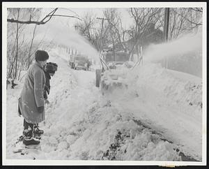 Pushing Back Snow in 10-foot drifts at Cummaquid, rotary plow enthralls young audience as it fights aftermath of Cape storm. Progress was slow-about a mile an hour.