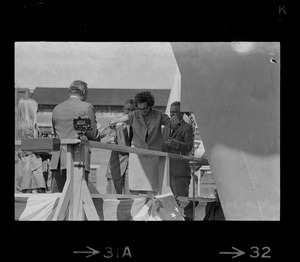 Mrs. Barry Shillito, wife of the Assistant Secretary of Defense, wields a heavy hand as she smashes champagne bottle on bow of USS Mount Vernon at Quincy christening