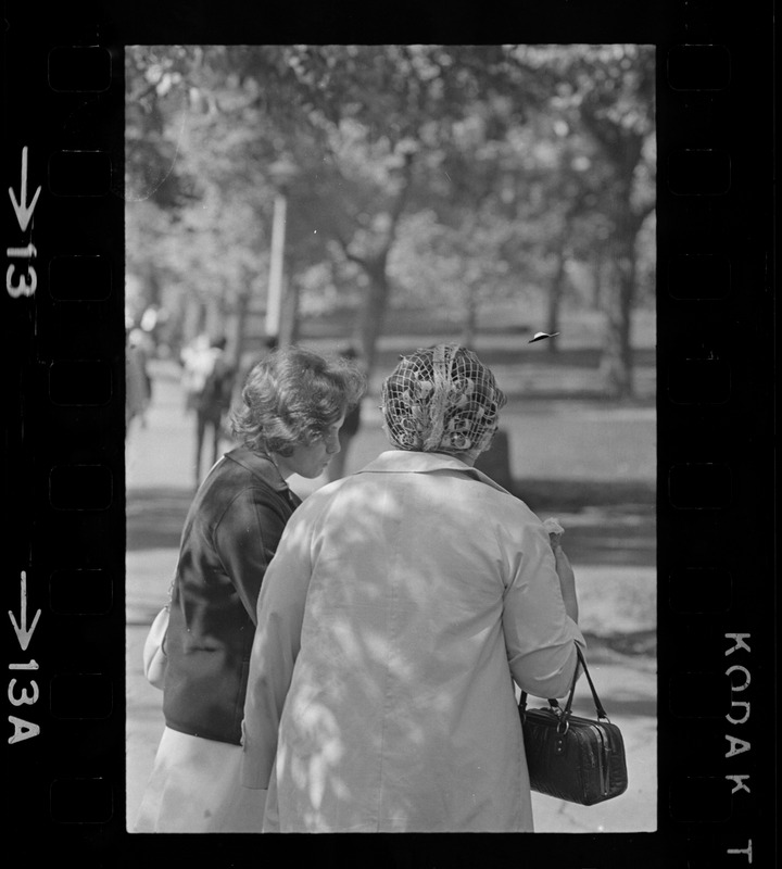 Two women, one with hair curlers, talking outside