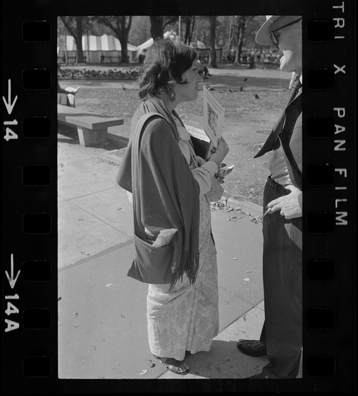 A woman talking to and handing a pamphlet of A.C. Bhaktivedanta essays to a man