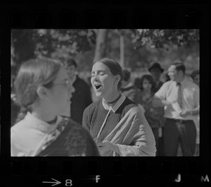 A woman singing outside with spectators in the background