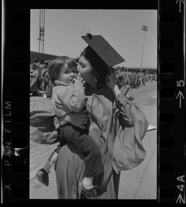 Boston University graduate holding and kissing a child