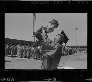Boston University graduate holding child in the air
