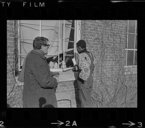 Reggie Sapp and another man speak to an occupier through a window of Ford Hall at Brandeis University during sit-in