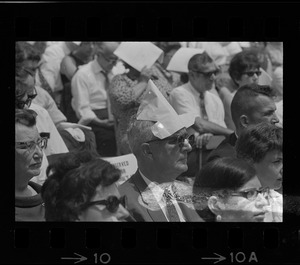 Man in audience at Brandeis University commencement wearing a paper hat, presumably for sun protection