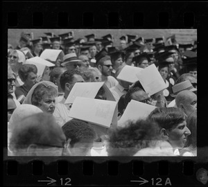Audience members at Brandeis University commencement with programs over their heads, presumably for sun protection