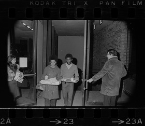 Black students at Brandeis University walking through doorway with trays of food during protest and student occupation of Ford Hall