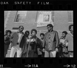 Surrounded by backers, Sharon Hammond of Boston, a sophomore at Brandeis University, speaks beneath the banner of Malcom X University, the name given to Ford Hall by Black students demanding Black instructors for Black oriented courses