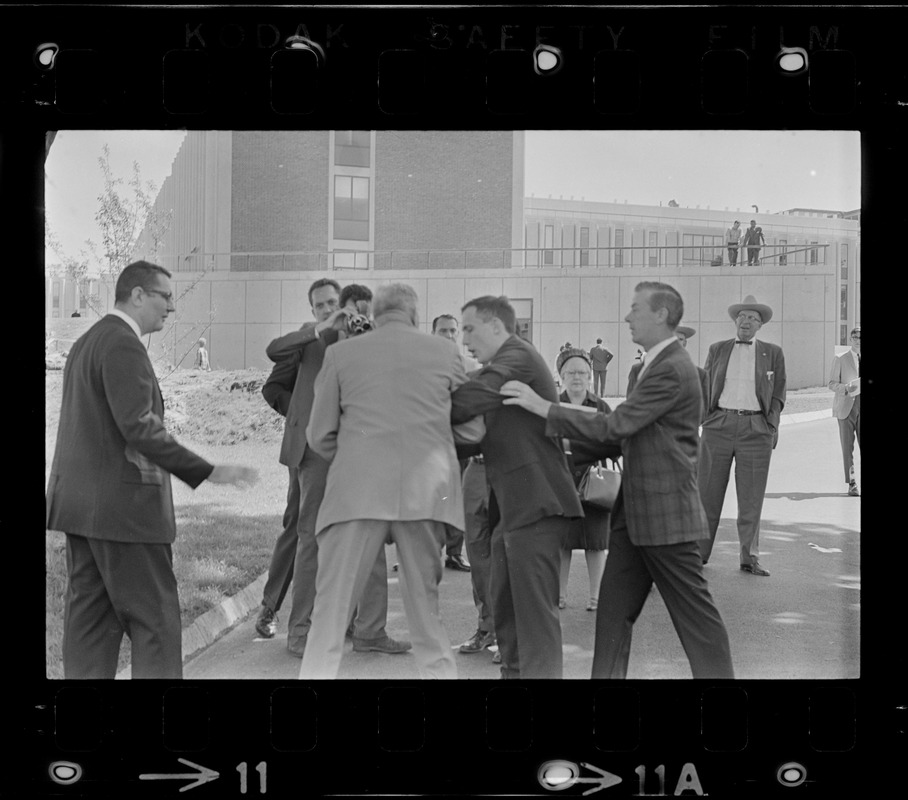 Screaming, Stephen Golin, 26 of Leach Lane, Natick, a graduate student and Ph.D candidate is dragged from Brandeis University Campus by Det. Arthur McGonigle of the Waltham Police and another detective after Golin refused to stop passing out anti-Vietnam war literature at the commencement exercises