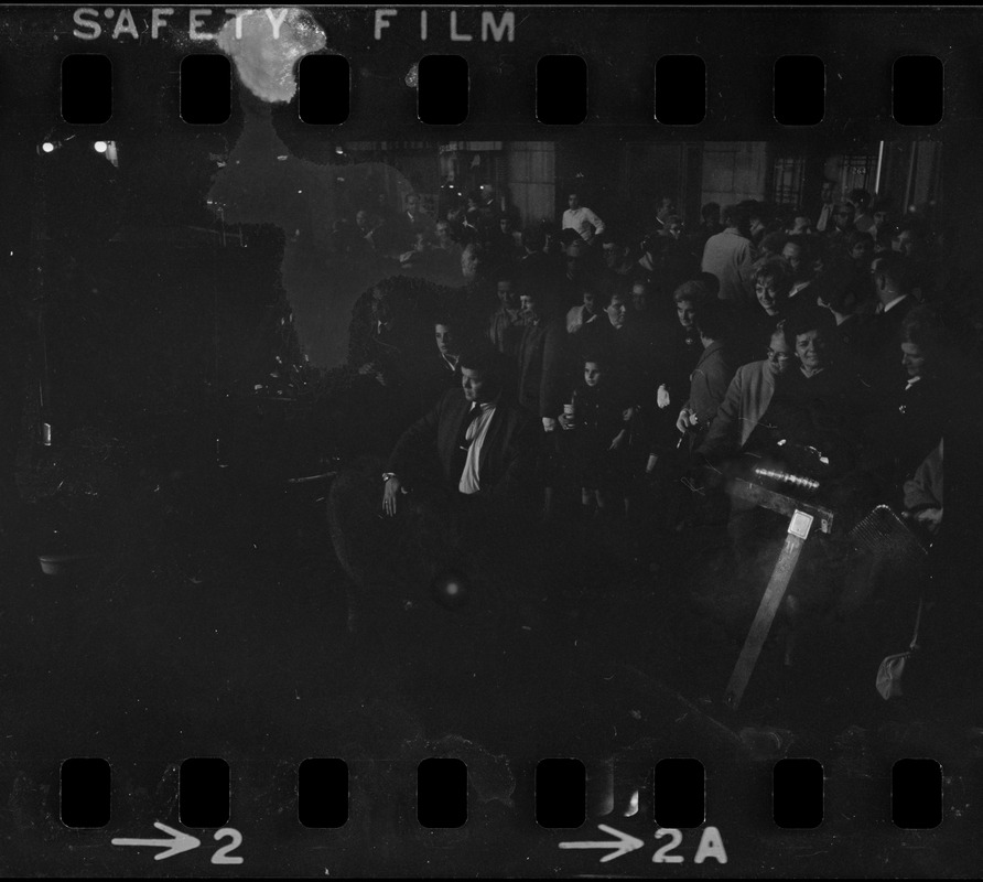 Dark view of crowd on sidewalk surrounding a small elephant outside the Sack Theater on the occasion of the "Camelot" film premiere