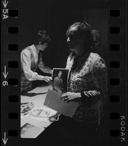 Wife of serviceman believed to be POW's being held by Communists, Mrs. Joseph Dunn, Randolph (believes husband was shot down over China) holds photographs while preparing to hang a poster in Boston City Hall