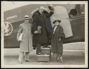 Saying "I will answer Curley tomorrow night," Mayor Mansfield East Boston airport today for New York. he was accompanied by Mrs. M and his secretary, Joseph Mellyn, shown on left.