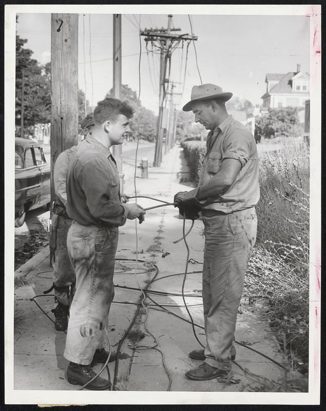 Splicing a Cable - Unidentified members of an electric line crew splice a cable as they rush about their task of restringing wires and repairing breaks, attempting to restore power to the Greater Boston area.