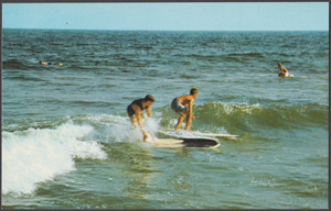 Two men surfing, swimmers in background